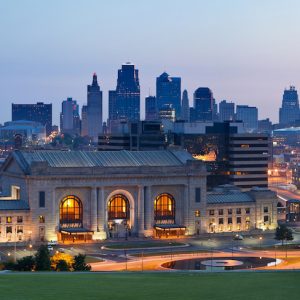 Panoramic view of Kansas City's skyline at twilight, featuring the iconic Union Station and illuminated buildings in the background.