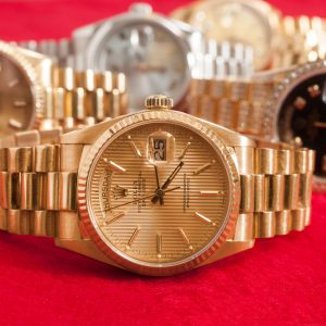 A collection of elegant luxury watches with gold and silver tones displayed on a red background, emphasizing their intricate designs.
