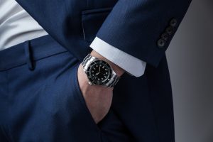 Man on a blue suit and white shirt wearing a Rolex watch