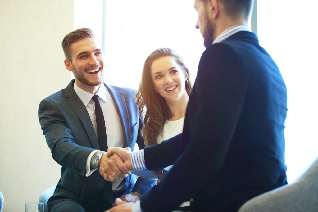 A couple wearing suit talking to a professional loan expert and shaking hands