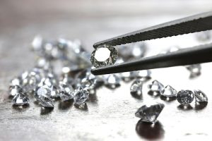 Diamond in tweezers with loose diamonds below
