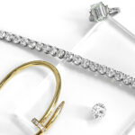 Image of gold nail bracelet with diamonds, a white gold diamond tennis bracelet, a loose round diamond, and an emerald diamond engagement ring - Diamond Banc | The Nation's Premier Diamond Buyer
