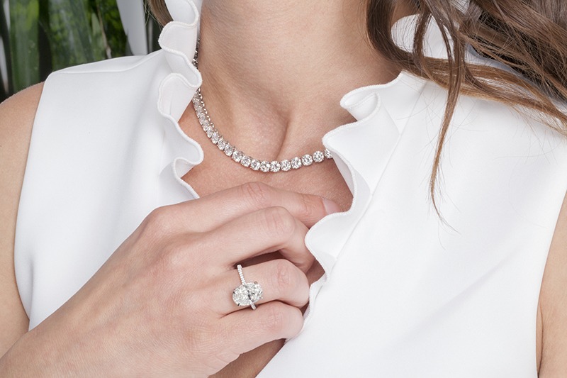 woman's neck with a diamond necklace and a diamond ring