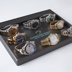 A display of 8 luxury watches, featuring various styles and colors, arranged in a sleek tray with "Diamond Banc" logo prominently shown.