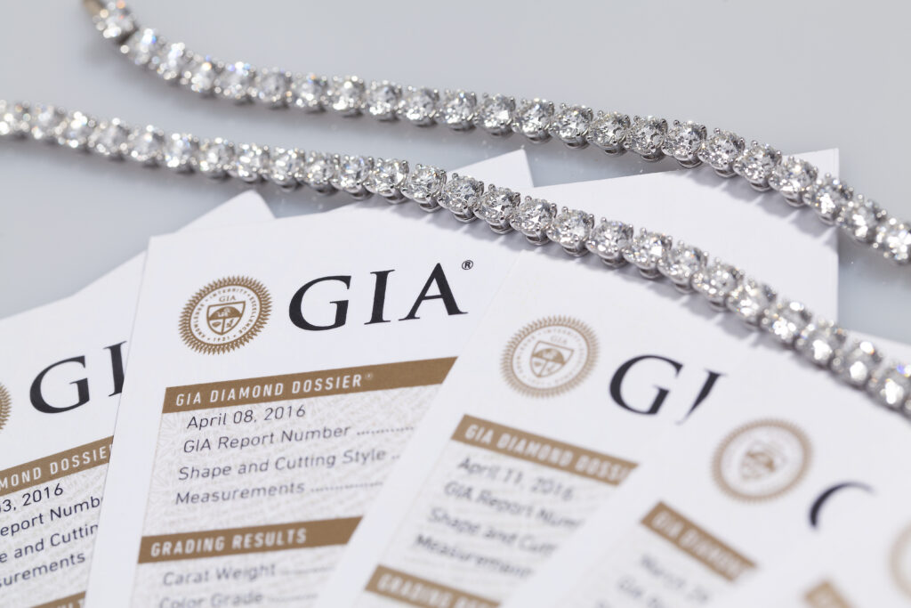 Close-up of GIA diamond certificates alongside a shimmering diamond necklace against a light background.