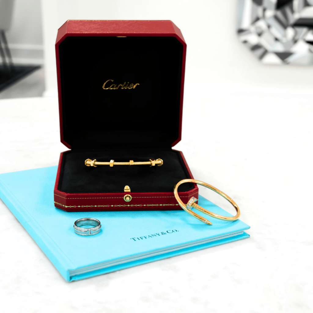 Cartier gold bracelet on top of Tiffany & Co. catalog with a diamond ring and another gold bracelet