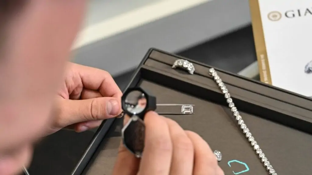 Diamond Banc expert examining a diamond beside its GIA grading report