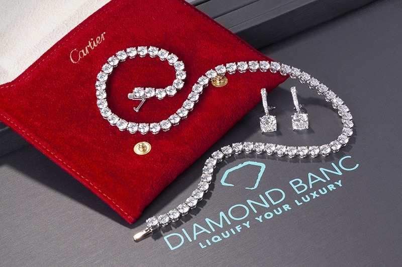 A luxurious Cartier jewelry set featuring a sparkling diamond bracelet and earrings on a red pouch, with Diamond Banc branding below.