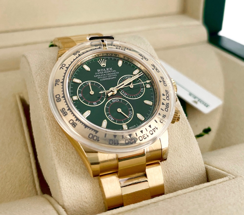 	
A stunning gold Rolex chronograph watch with a green dial is showcased in its original box.